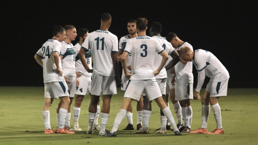  The Coastal men’s soccer team regroups during a night time game.