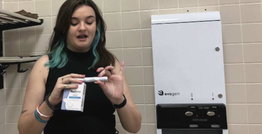 SGA’s Vice President of Finance Ryleigh Gregory demonstrating how to use free menstrual product dispensers.