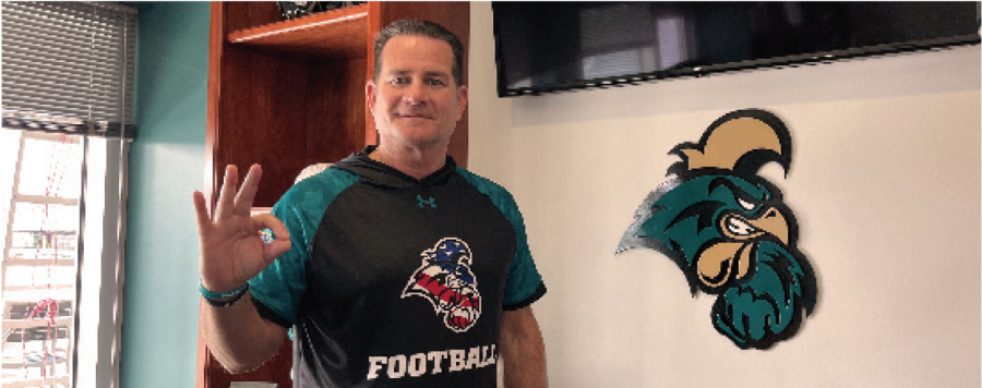 Head coach Tim Beck sporting a “chants up” in his new office overlooking the teal field in Brooks Stadium.