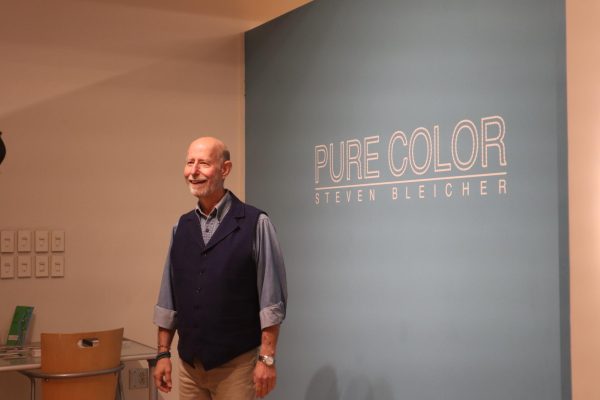 Professor Steven Bleicher in front of the sign for his collection Pure Color in the Rebecca Randall Bryan Art Gallery.