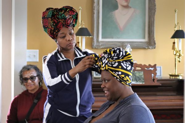 Kim Clora, founder of the Jacqueline Rodgers Foundation, demonstrates hair wrapping on Assistant Professor of visual arts Ashlyn Pope as a part of the Gullah Geechee Community Day in the Bryan House on Feb. 24. Historically, textured hair was considered inappropriate and tempting, according to Clora. The reclaimed art of hair wrapping values design and height to match the individual’s mood. 
