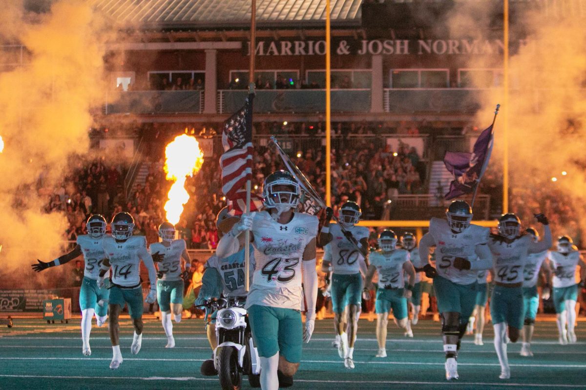 The Coastal Carolina Chanticleers run out onto the teal turf ahead of kickoff. 